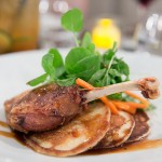 Crispy duck leg on a bed of fluffy pancakes