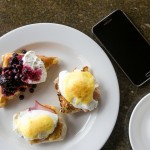 Eggs benedict, waffle with toppings, coffee and a Samsung Galaxy S5