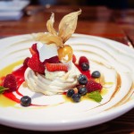 French meringue with lemon curd, topped with fresh fruit and finished off with passionfruit syrup, raspberry coulis and a mint garnish