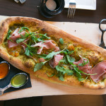 "The One Eighty" is a hand stretched pizza with proscuitto, smoked provolone, pesto and arugula. It comes with spicy and chive infused extra virgin olive oils
