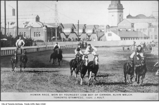 Item consists of a photograph showing cowboys engaged in trick horse-riding. The race was "won by youngest cow boy of Canada, Alvin Welch."