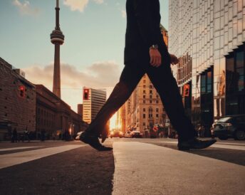 Guy walking in downtown Toronto in front of CN tower